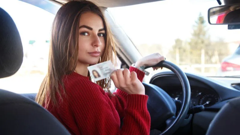 Woman holding driver's license in car