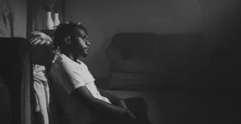 black and white image of man sitting down in dimly lit room